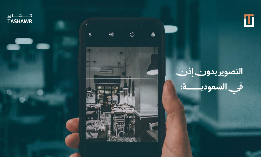 يد تمسك هاتفاً ذكياً يصور مكتبًا، يمثل قضايا التصوير بدون إذن في السعودية والخصوصية الرقمية